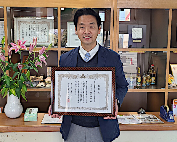 宮崎県地域経済振興100年企業顕彰の賞状を手にする黒木社長